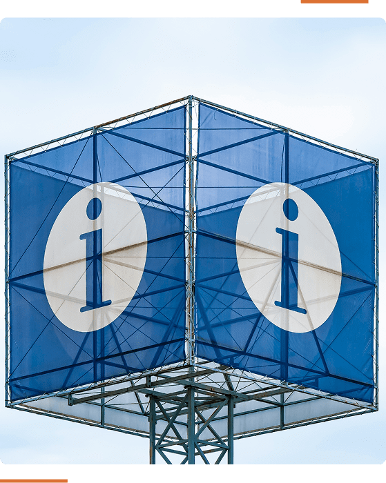 A blue and white information sign shaped like a cube is elevated on a metal pole against a clear sky.