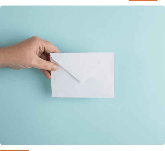 A hand holds a white envelope against a light blue background.